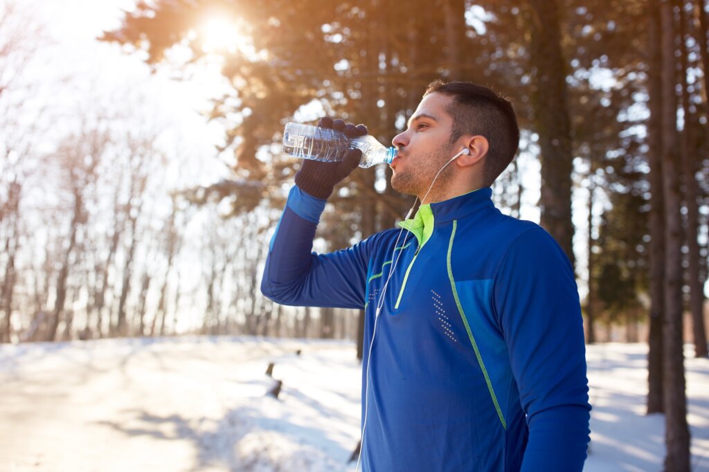 Male refreshes with water after running in woods