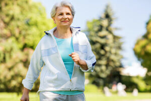 fitness, sport and healthy lifestyle concept - senior woman running along summer park