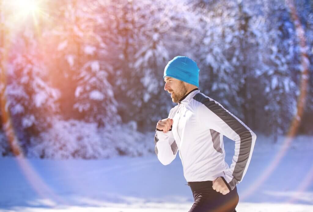 young fit man jogging in the snow exercising during the winter