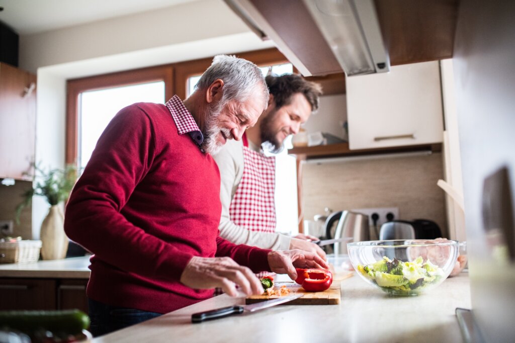 Hipster son with his senior father cooking in the kitchen. Two generations indoors. lifestyle choices for healthy heart