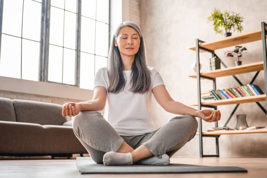 Grey-haired mature caucasian woman meditating at home
