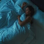 woman sleeping alone in big bed at night, top view, blue toned. sleep hygiene tips