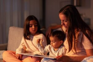 Mom telling a story to her children at night sitting on the couch
