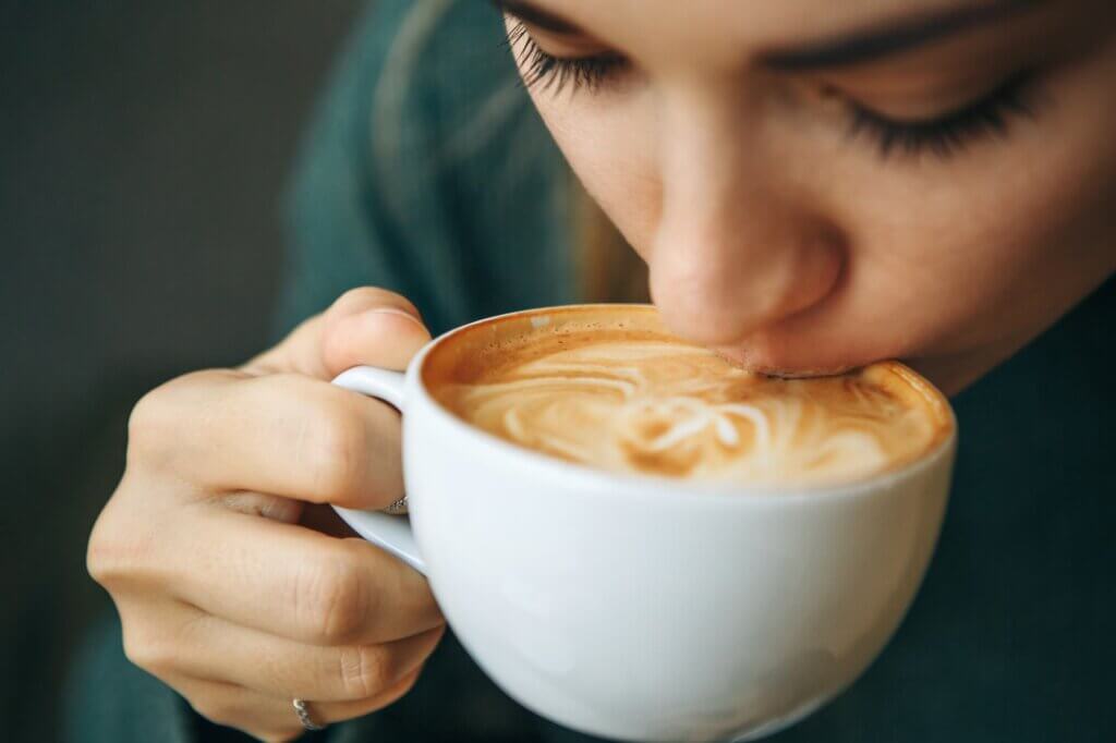 Close up girl is drinking coffee. how much caffeine per day