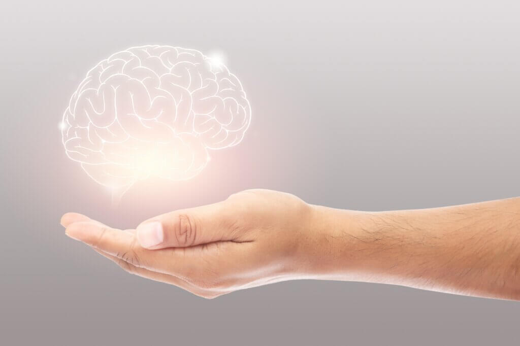 Man holding brain illustration against gray wall background. Concept with mental health protection and care.