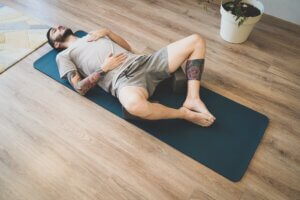 Tired Young man lying on a yoga mat after workout. Man practicing yoga and meditation at home. A series of yoga poses. Lifestyle concept