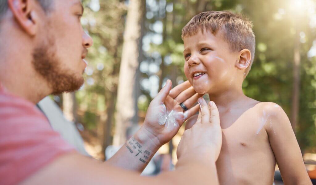 Father apply sunscreen on child face for protection or safety while camping in a forest or woods for vacation or holiday. Lotion, cream and dad care for kid with skincare product in outdoor adventure. how to choose sunscreen