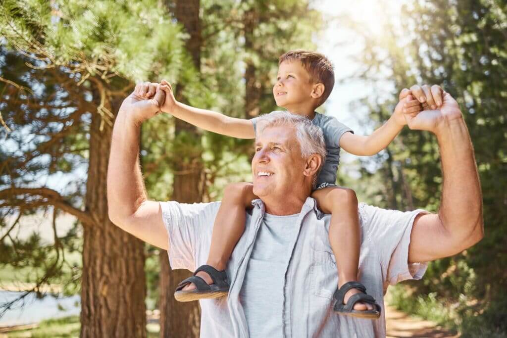 gracefully aging man with his grandson sitting on is shoulders, smiling off into the distance