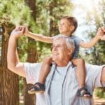 gracefully aging man with his grandson sitting on is shoulders, smiling off into the distance