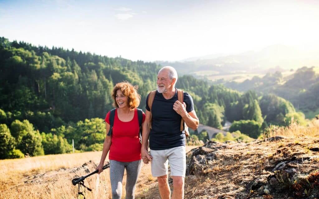 senior couple on a hike together to reduce their risks of high cholesterol by exercising