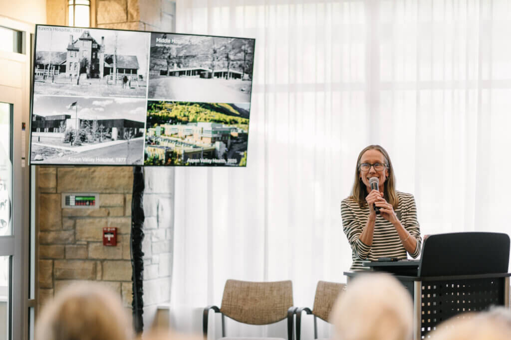 woman presenting in front of a tv screen