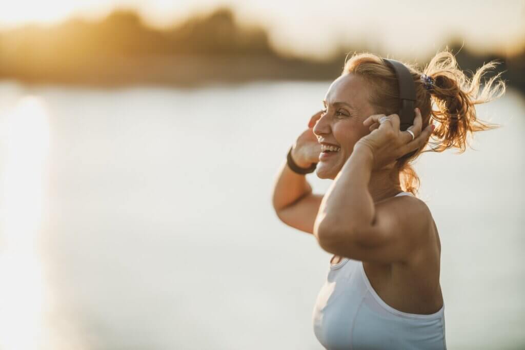 woman smiling while she puts on her running headphones