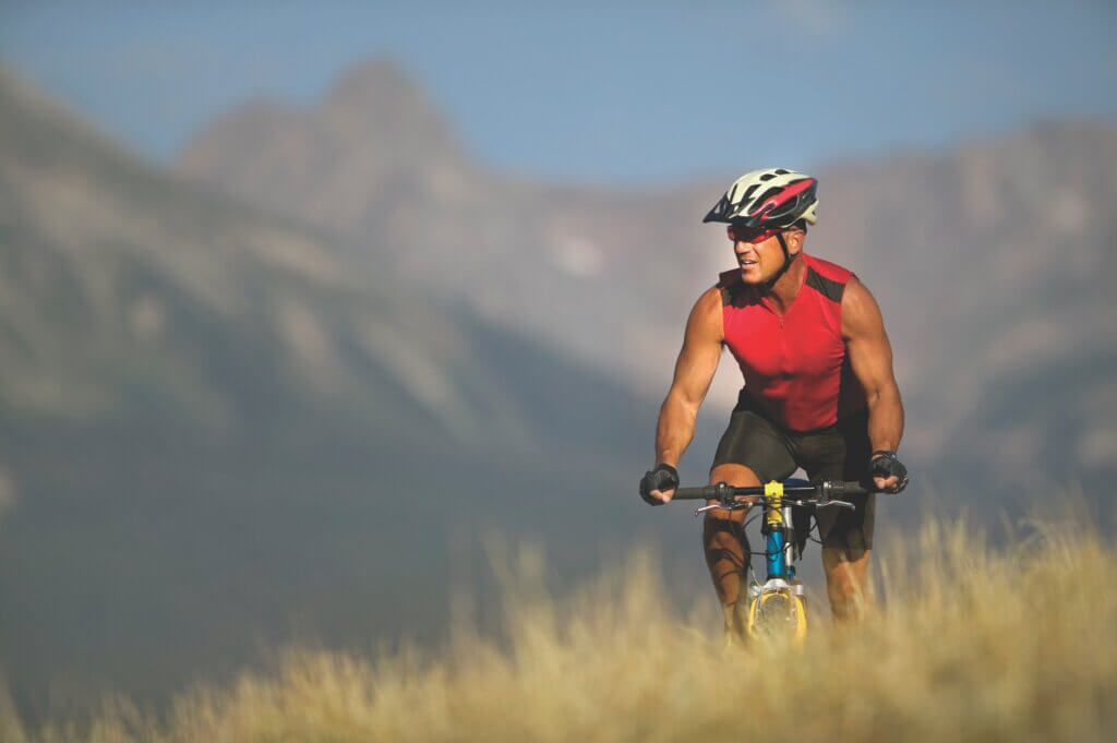 man promoting his the brain gut health connection by riding his bike in the mountains during a bright sunny day
