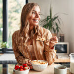 woman smiling while eating a bowl of cereal