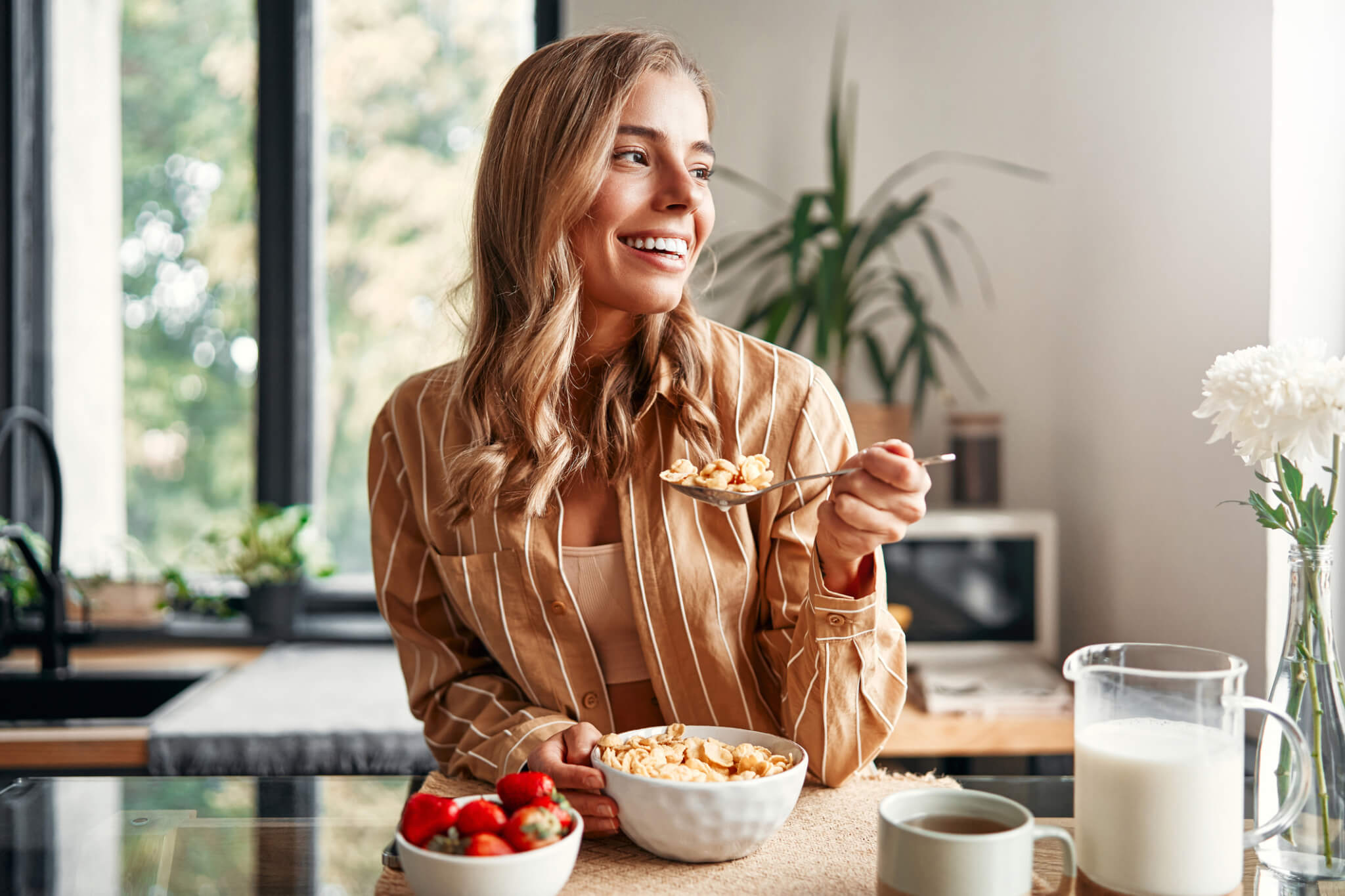woman smiling while eating a bowl of cereal
