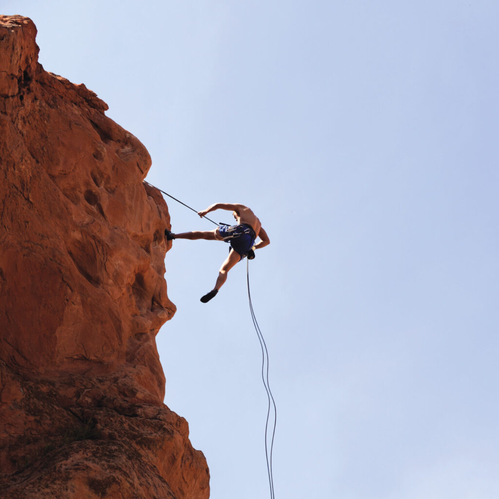 man rappelling from the side of a cliff