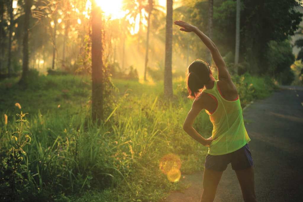 woman stretching before she goes on a run through the forest