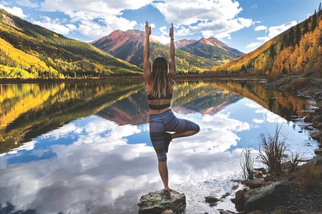 woman doing yoga by a lake in the mountains