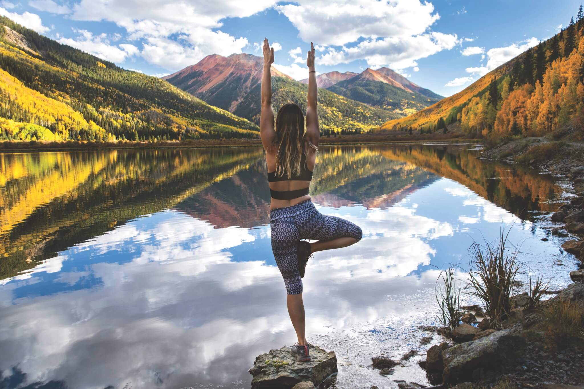 woman doing yoga by a lake in the mountains