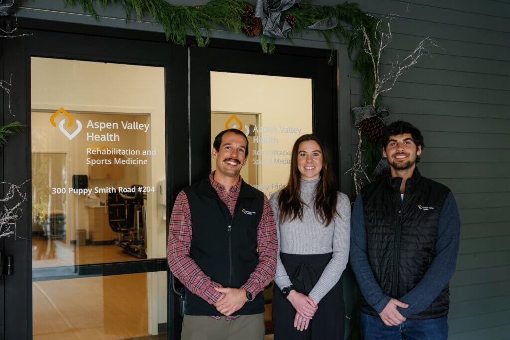 three people standing outside the front doors of the Aspen Valley Health rehabilitation and sports medicine location in downtown