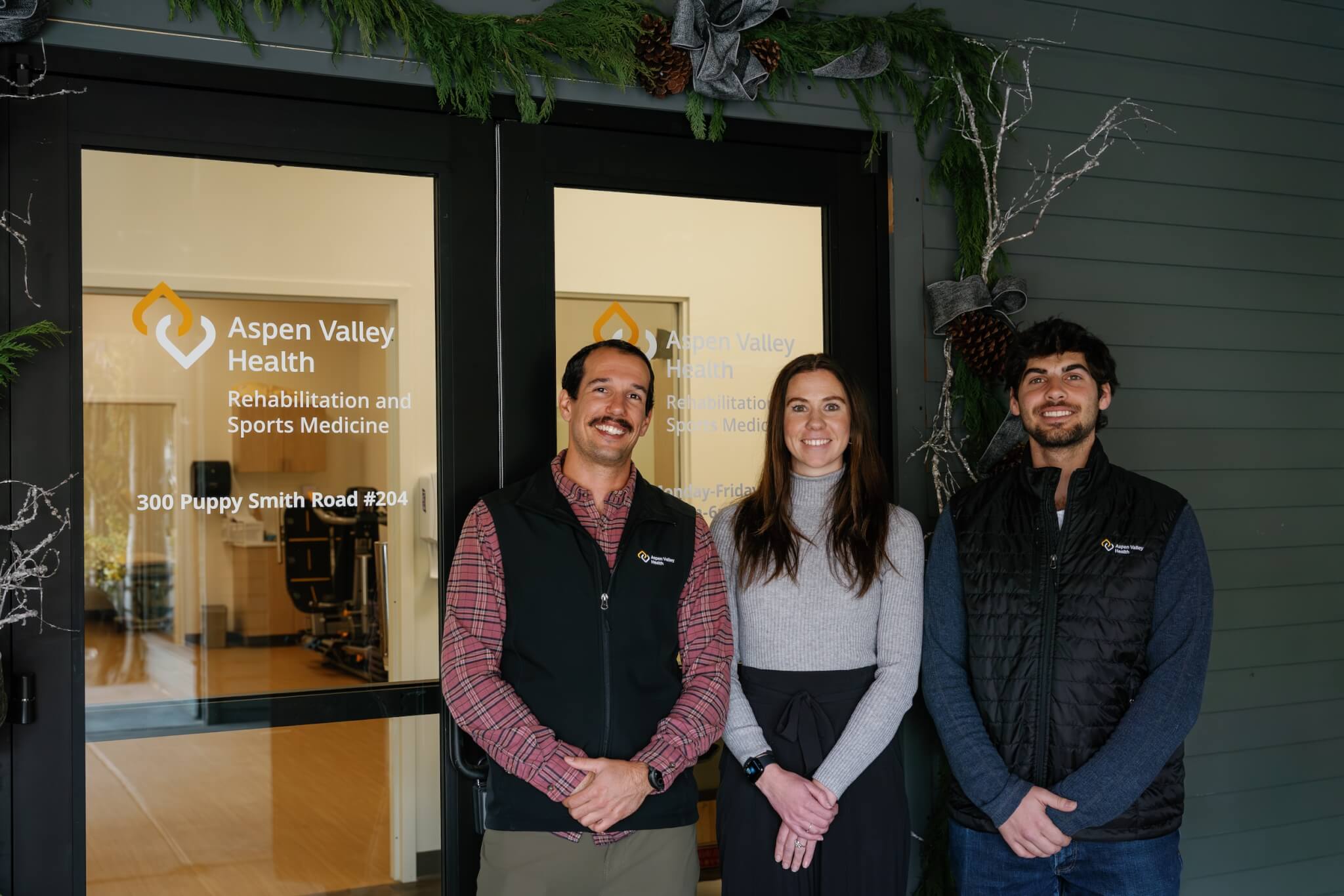 three people standing outside the front doors of the Aspen Valley Health rehabilitation and sports medicine location in downtown