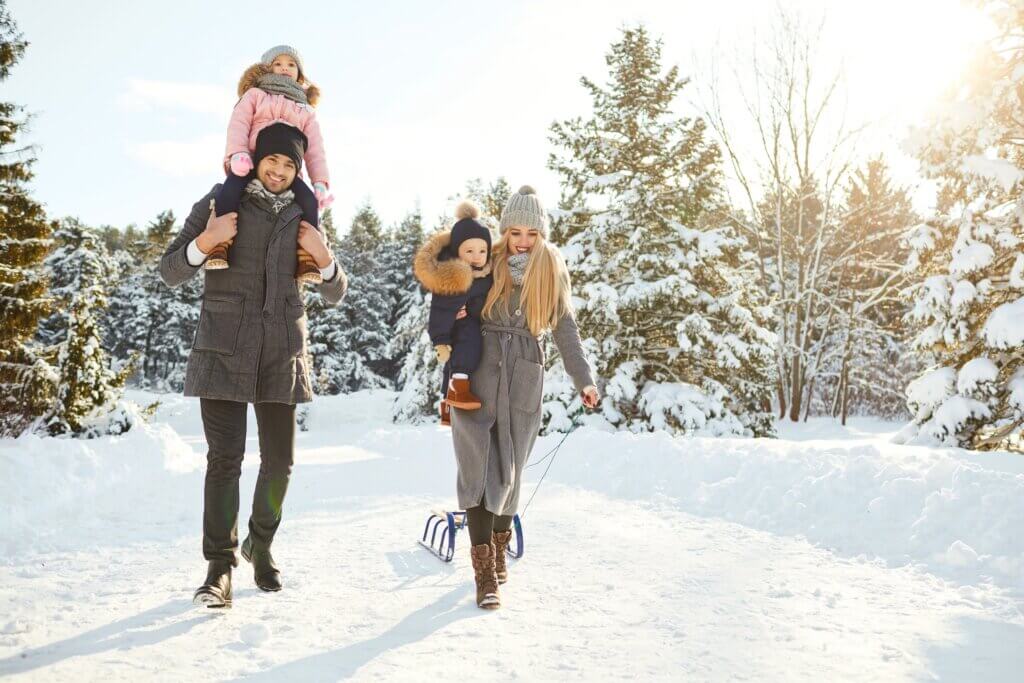 family with young kids walking through a snowy winter landscape so they can experience the effects of light therapy on anxiety and seasonal affective disorder