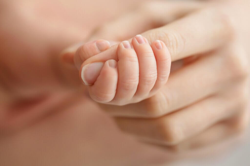close up image of a baby holding moms finger