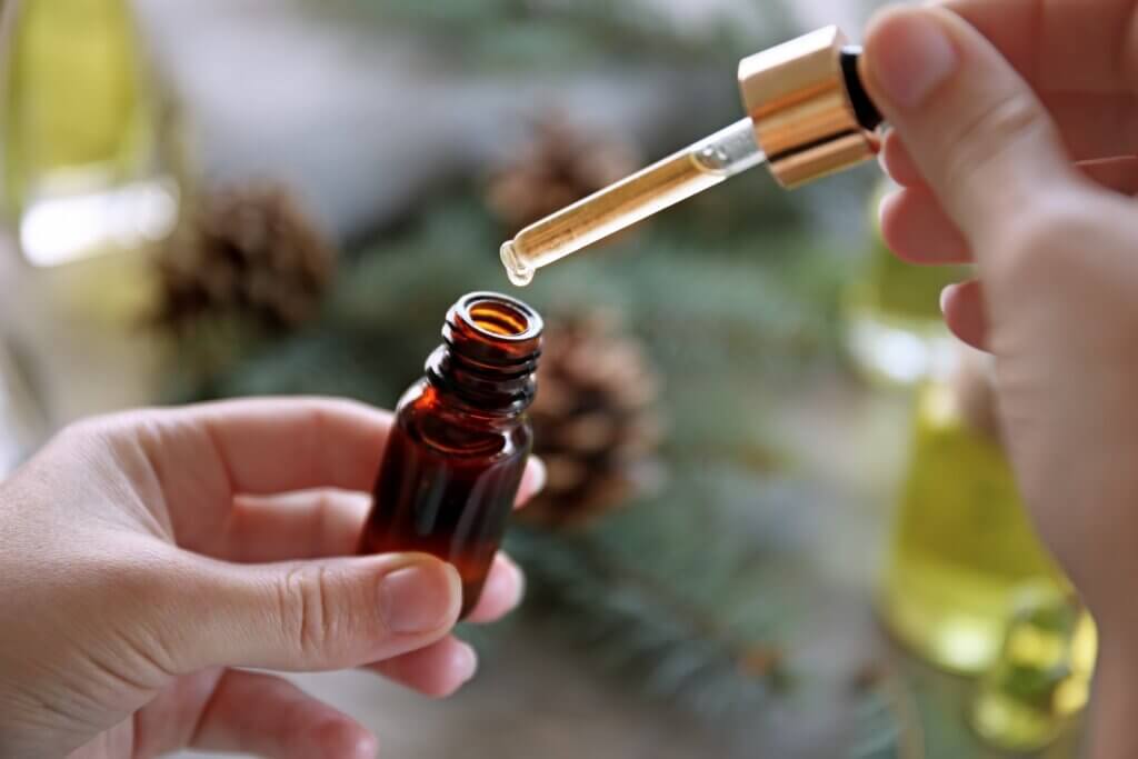 hands using a dropper to extract essential oils from a bottle