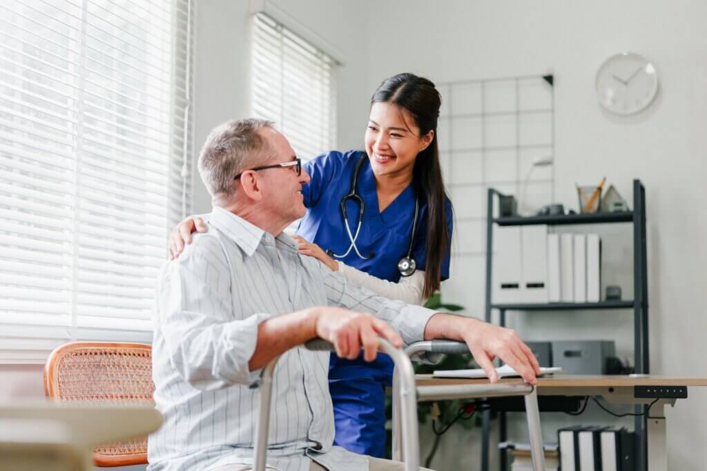 nurse helping a man in a walker to stand up