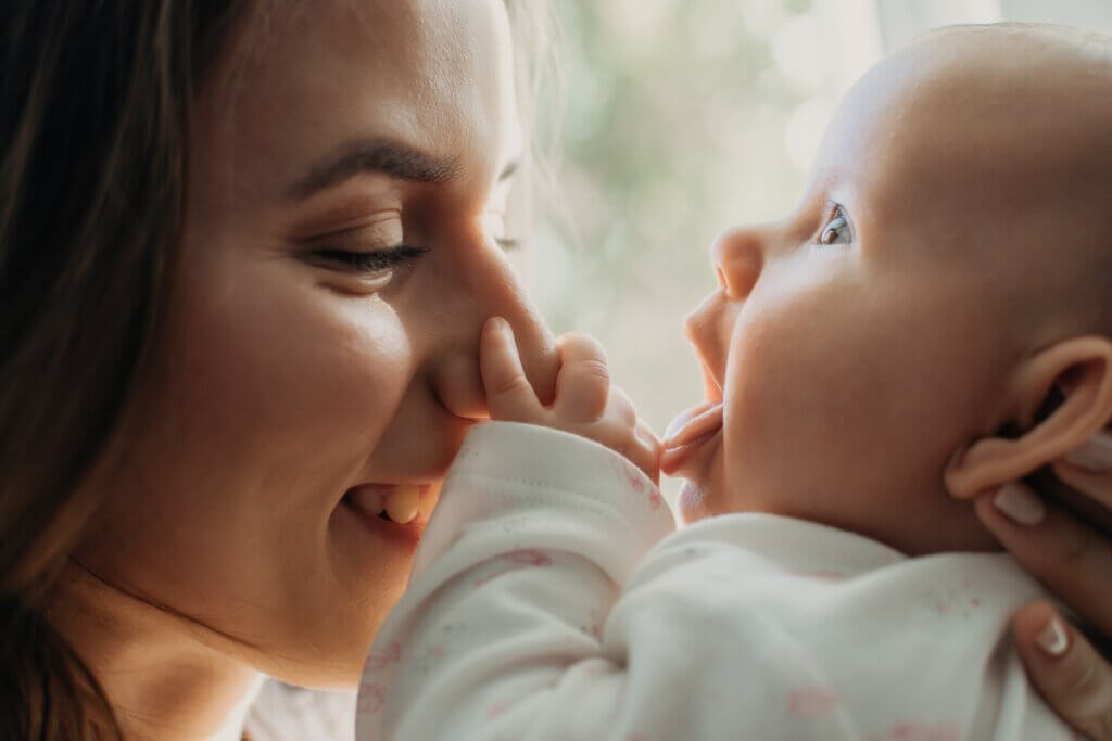 baby sticking her tongue out and holding her moms nose