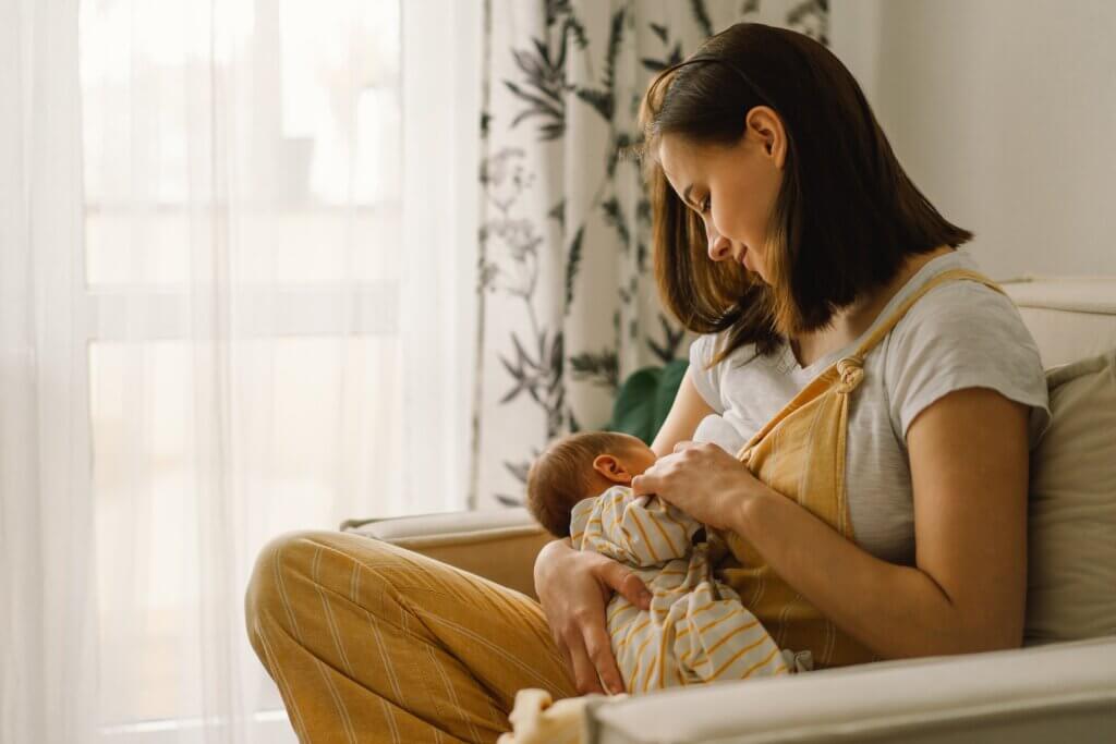 mom sitting on a chair and breastfeeding her baby