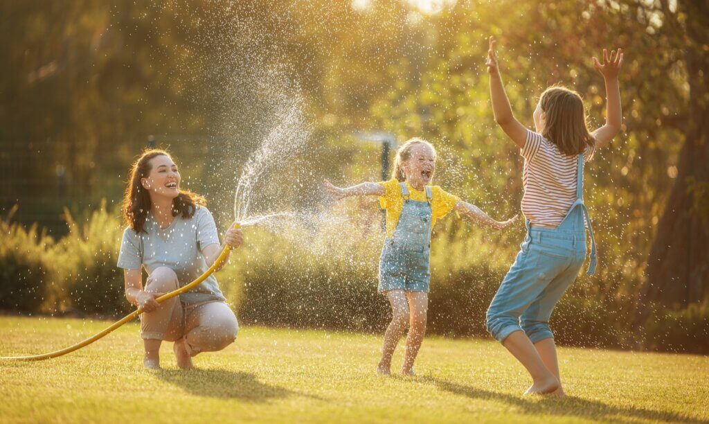 woman who had an endoscopy procedure to address her digestion issues playing her her two daughter in her yard and spraying them with a hose