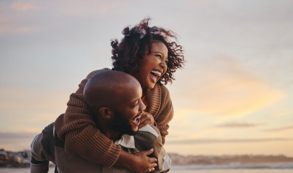 couple laughing and playing outside as a way to decompress and support their gut health through exercise