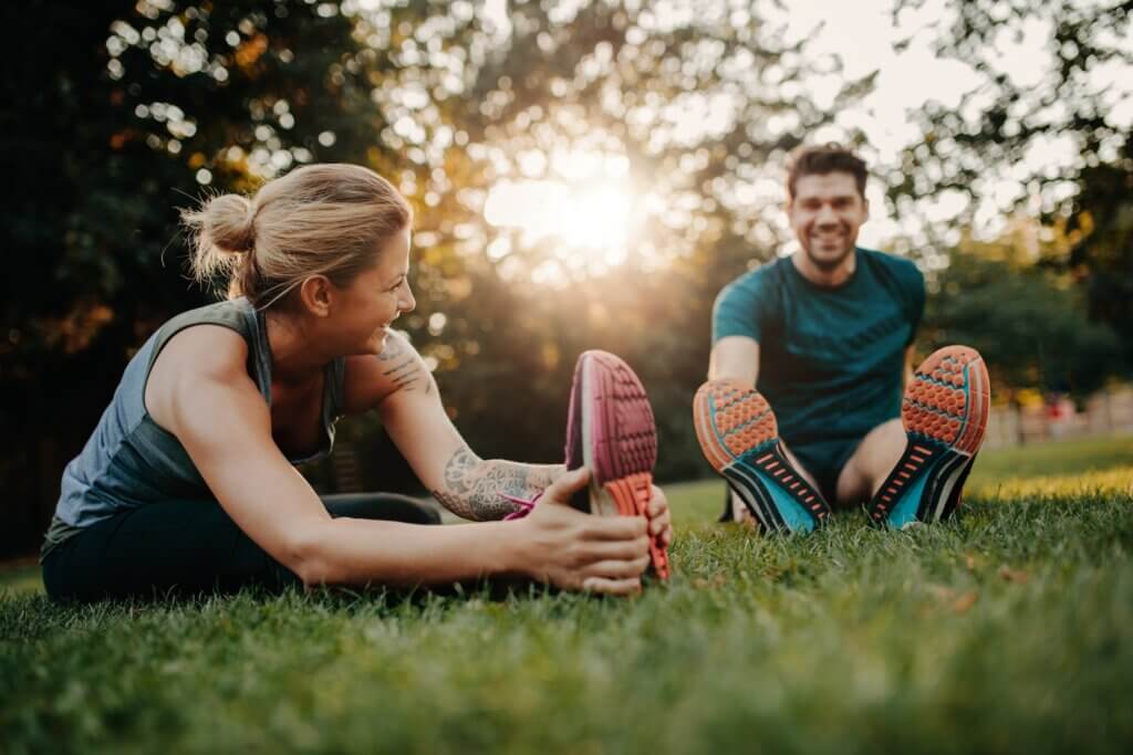couple sitting in a field and stretching after a run