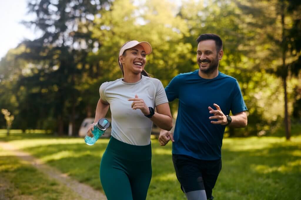 woman in a baseball cap jogging next to a man who is smiling at her