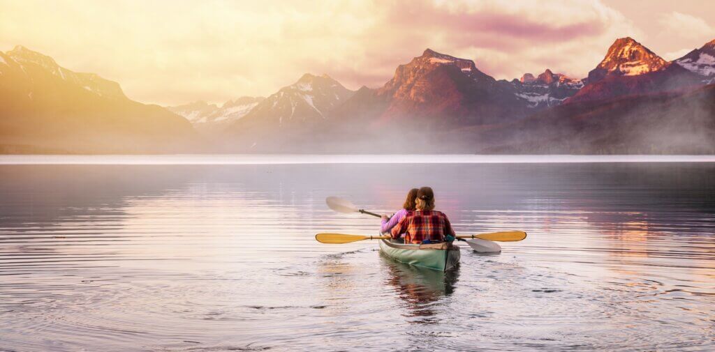 two people in a canoe paddling toward the mountains