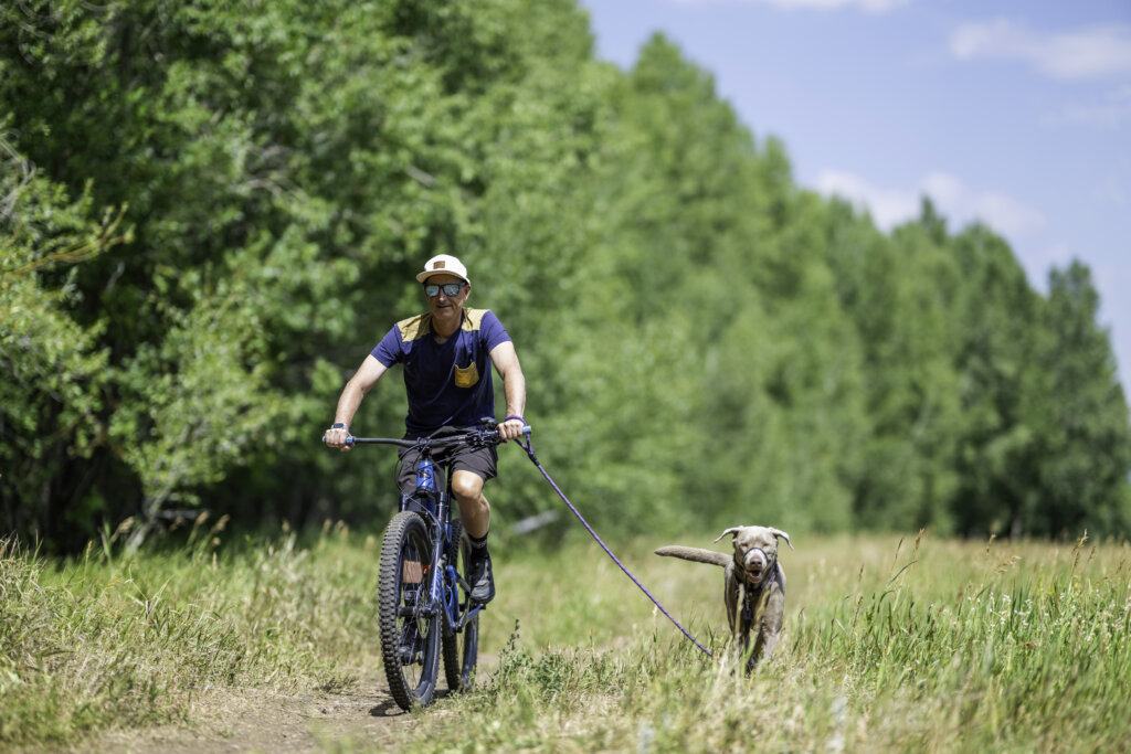 man riding his bike with his dog running beside him