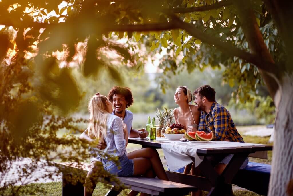 people sitting at a picnic table in the late afternoon and sharing a meal