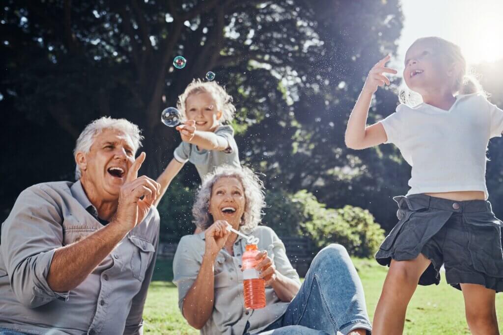 grandparents blowing bubbles outside with their two grandkids