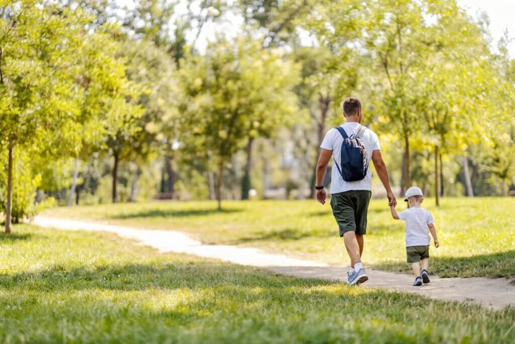man walking in the park with his young son after eating a meal to help with his silent acid reflux symptoms
