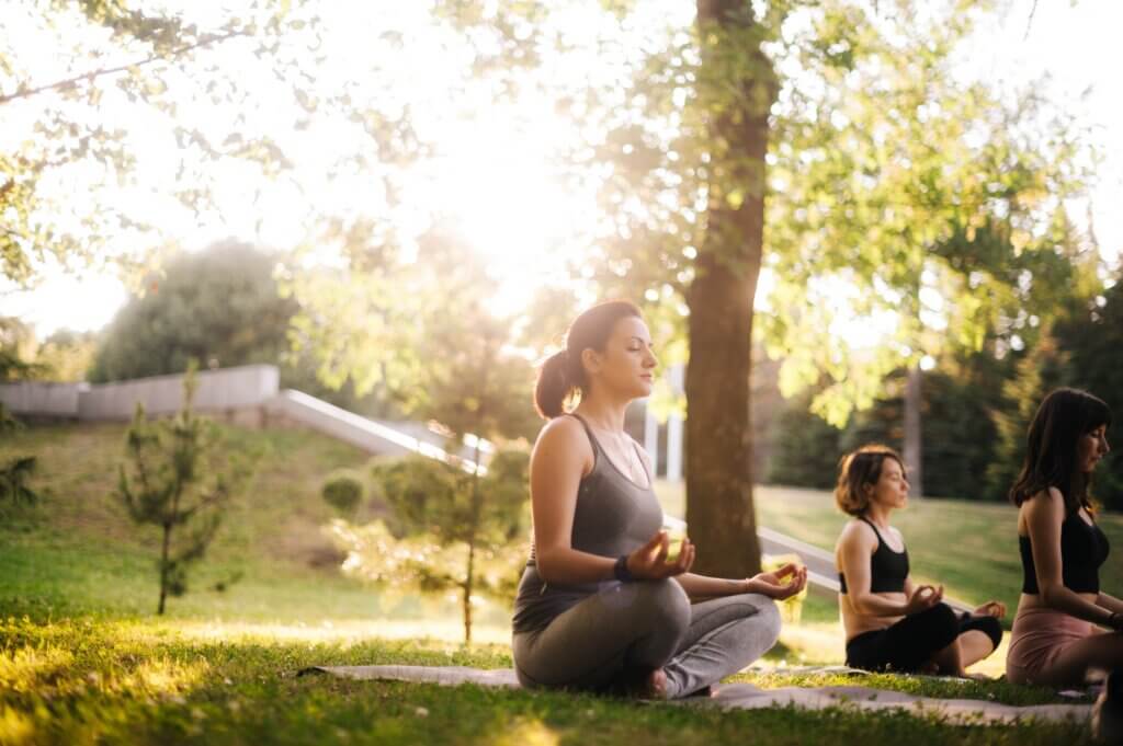 woman doing yoga in a park to reduce her stress levels and thus her symptoms of silent reflux