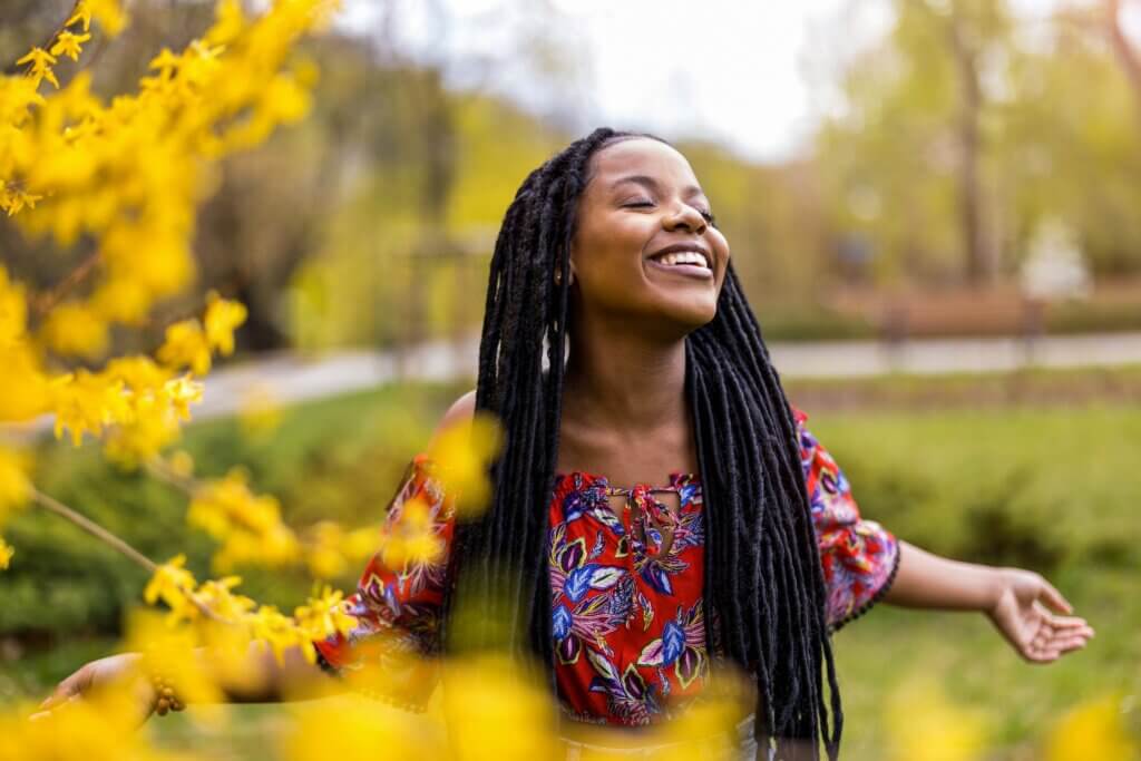 woman closing her eyes and holding her hands out and smiling